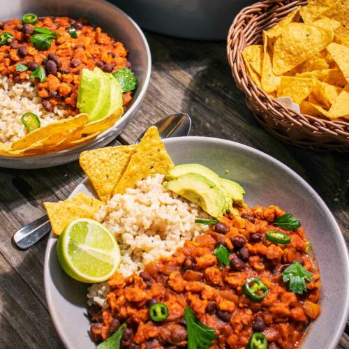 two bowls of vegan chilli with corn chips