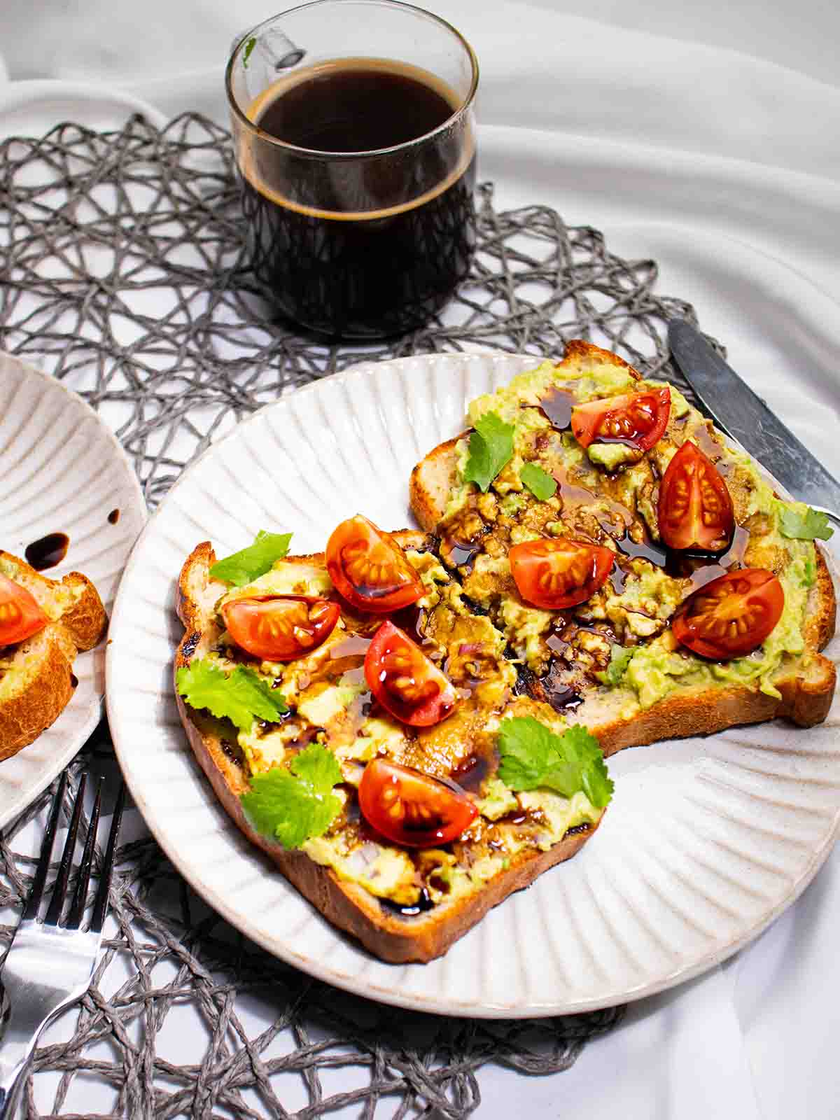 two pieces of avocado toast on a plate with coffee